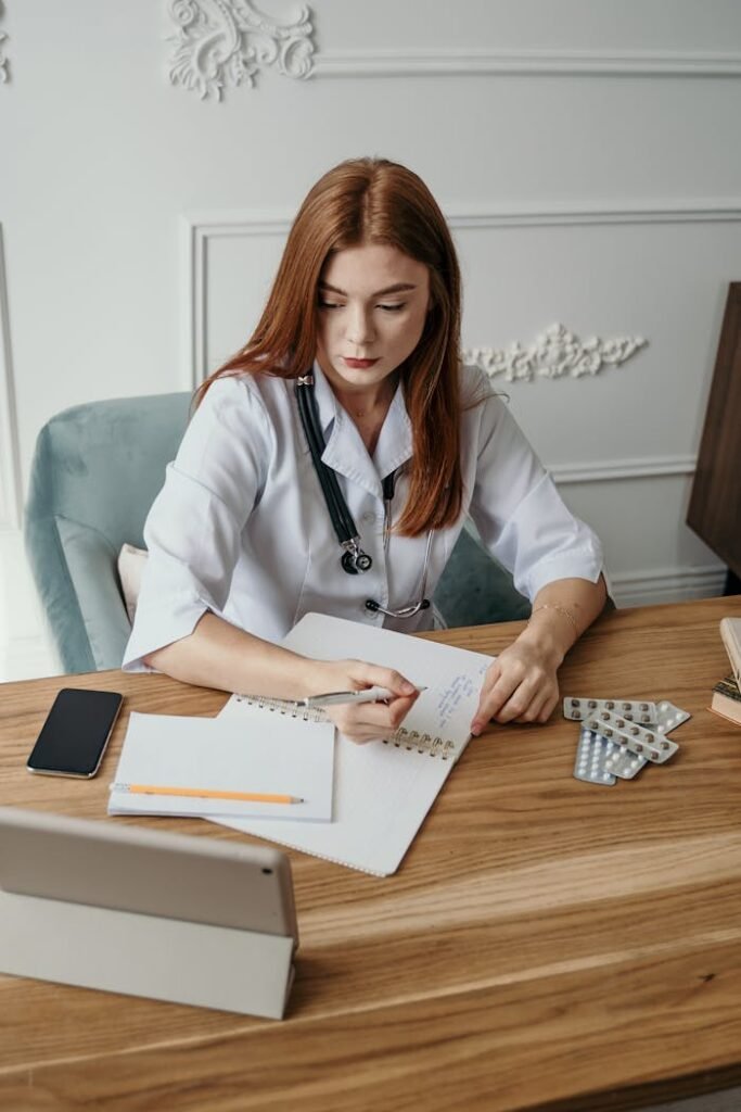 A female doctor writes notes at her desk in a clinical setting, focusing on healthcare tasks.